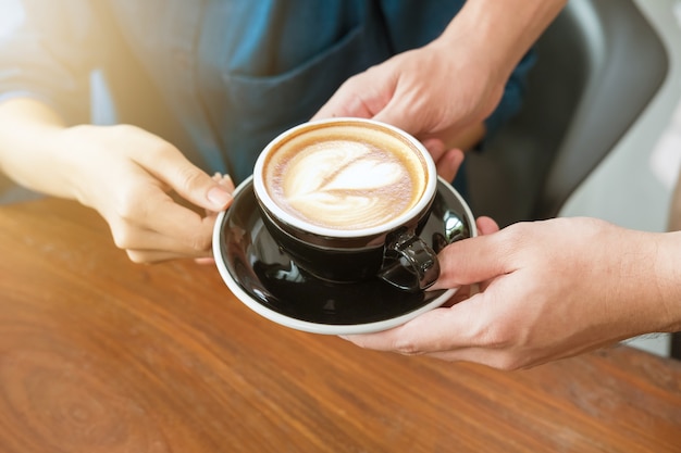 Close-up hand of a waitress serving a cup of coffee to customer. 