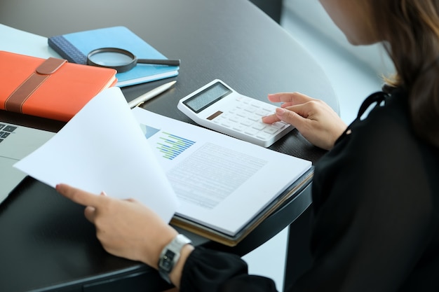 Close up hand woman doing finance and calculate on desk about cost at office