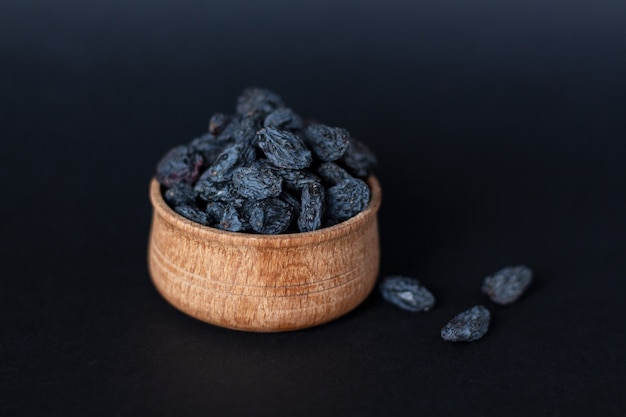 Close-up of handful of dark raisins on wood