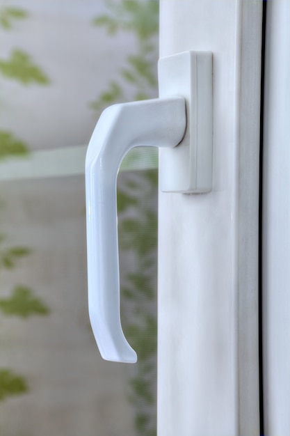 Close-up handle of pvc window locking mechanism with double glazing.