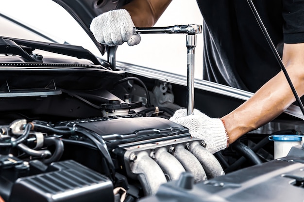 Close-up hands of auto mechanic using the wrench to maintenance car engine.