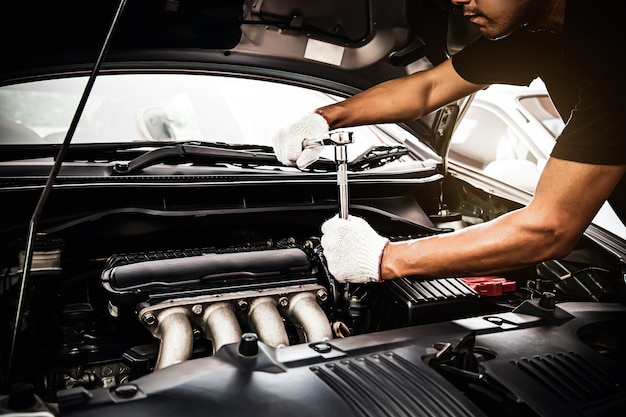 Close-up hands of auto mechanic using the wrench to maintenance car engine.