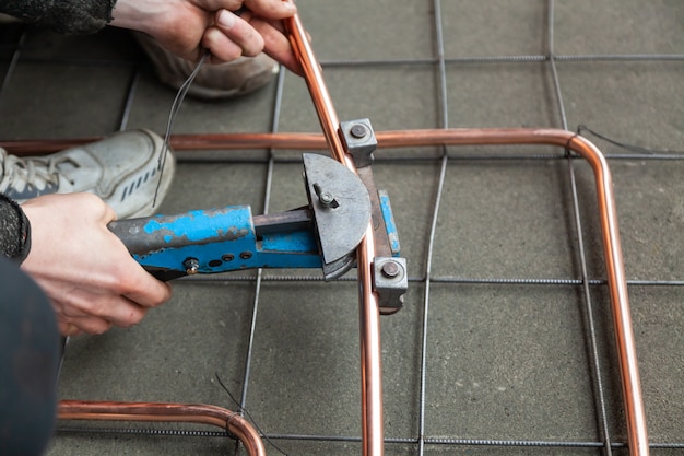 Close-up hands bends copper pipes by pipe bender