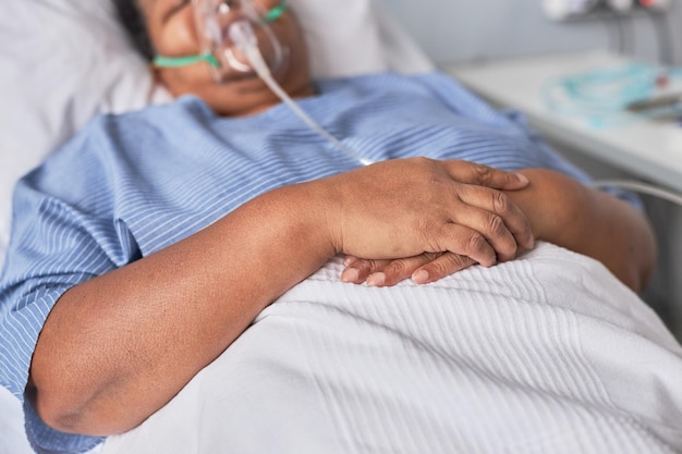 Close up of hands of black woman on bed in hospital room