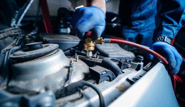 Close up hands of car mechanic connects air conditioning system in auto service