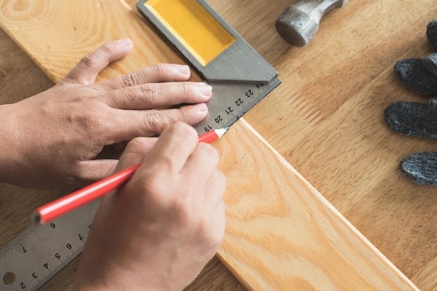 Close up hands of carpenter marking on wood.