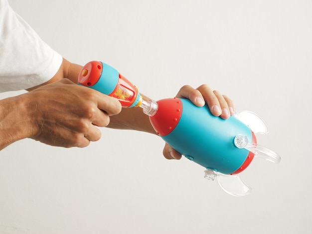 Close-up. Hands collect a toy blue spaceship rocket with the tool.