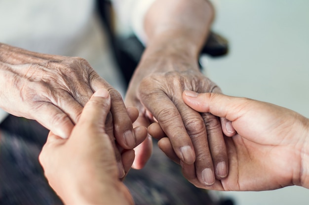 Close up hands of helping hands elderly home care. 