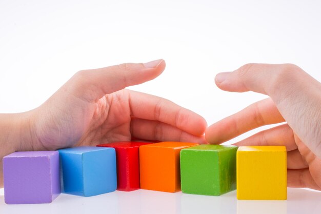 Photo close-up of hands holding colorful blocks over white background