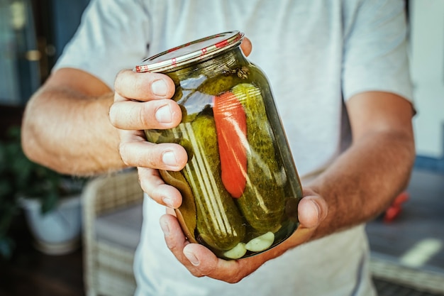 Close up of hands holding a jar with pickled cucumbers