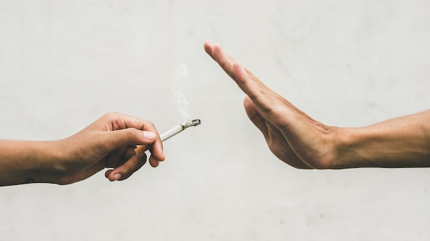 Close up hands of person refusing to smoke cigarette. negative attitude to smoking. Quitting smoking concept. Hand is refusing cigarette offer.