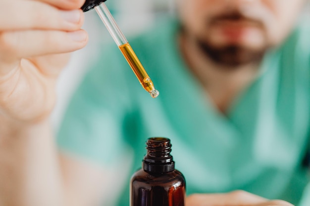 Close up of hands of scientists dropping marijuana oil for experimentation and research. CBD oil stu