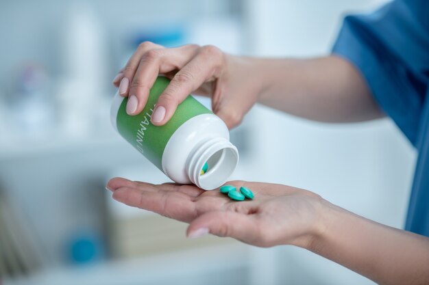 Close up of hands taking pills out of the bottle