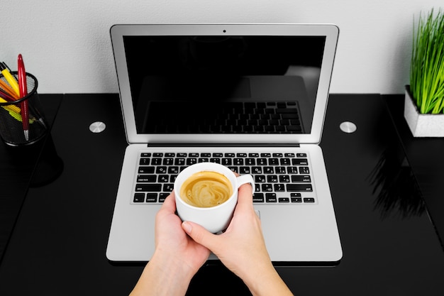 Photo close up of hands typing on a laptop in a coffee shop