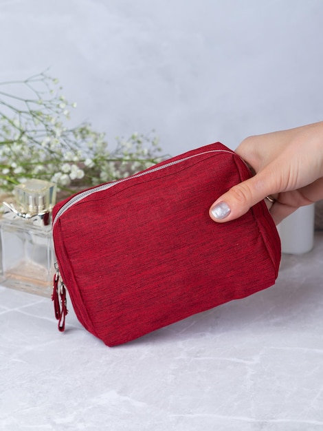 Close up of hands of unrecognisable woman taking makeup products from her red cosmetic bag