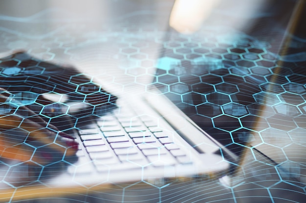 Close up of hands using laptop keyboard with creative blue hexagonal background Technology communication and network concept Double exposure