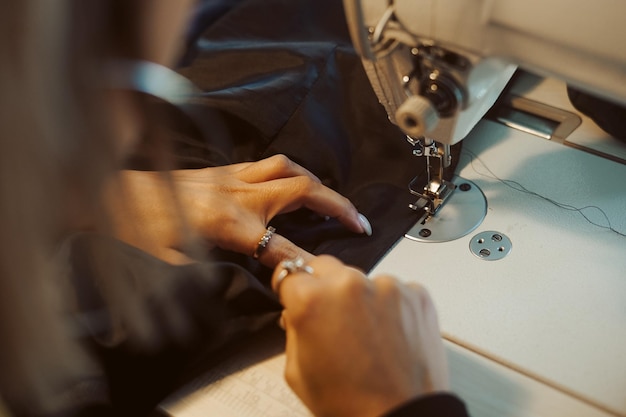 Close up of hands. Woman tailor working on sewing machine.