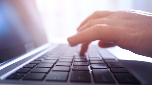 Close-up of hands of woman typing on laptop