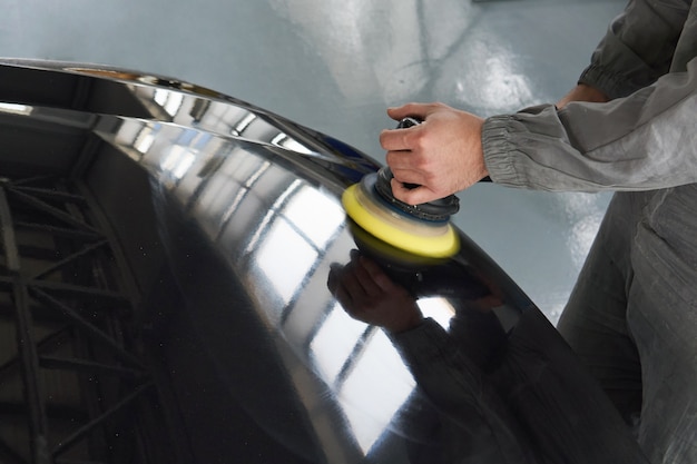 Close-up of hands worker using polisher to polish a gray car body in the workshop, Auto Mechanic Polishing Car