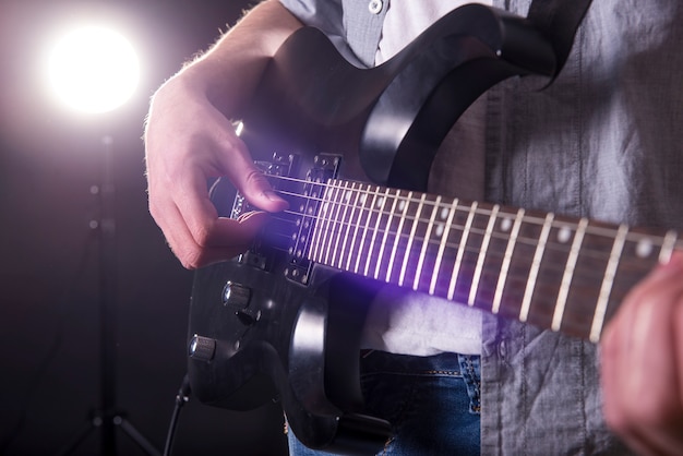 Close-up hands of young man is playing guitar.