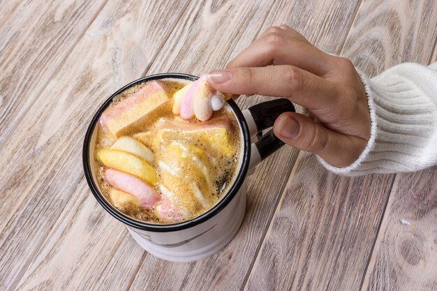 Close up hands of young woman female with manicure holding a cup of hot cocoa