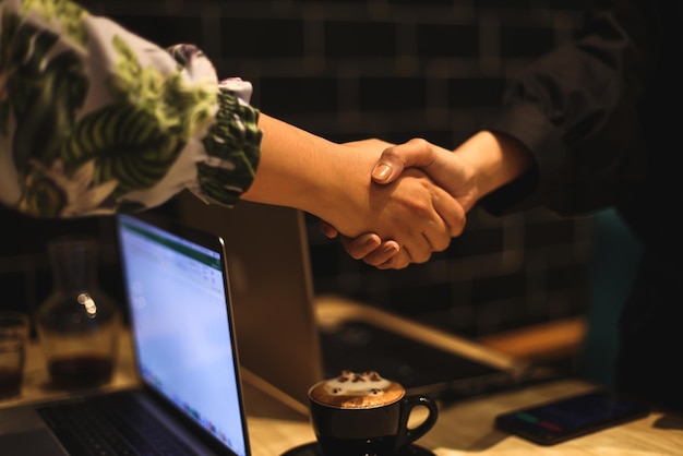 Close up of handshake with laptop devices in the background