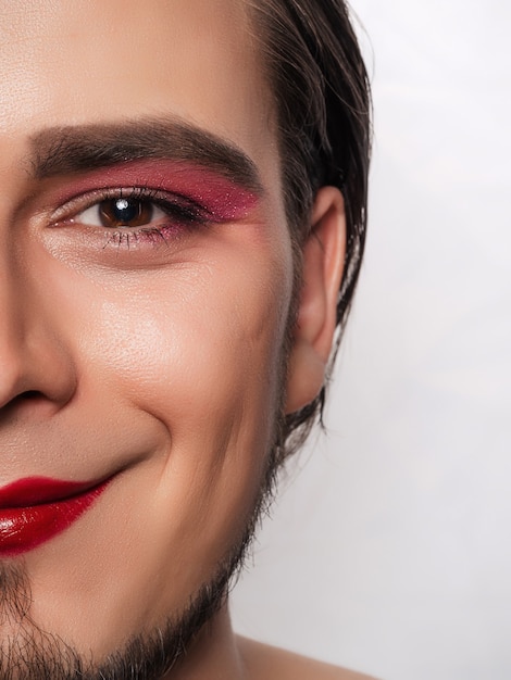 Close-up of a handsome bearded man doing his own makeup