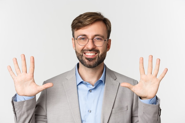 Close up of handsome bearded man in glasses and gray suit, showing number ten