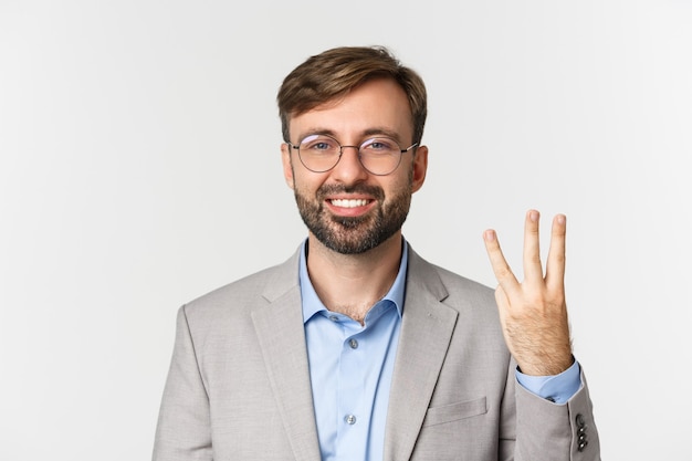 Close up of handsome bearded man in glasses and gray suit, showing number three