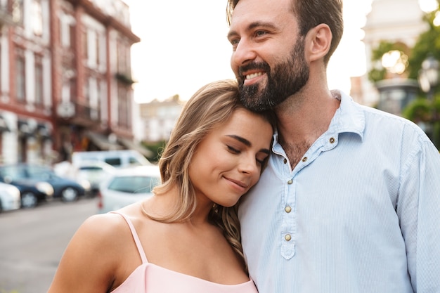 Close up of a happy beautiful couple embracing while standing at the city street, hugging