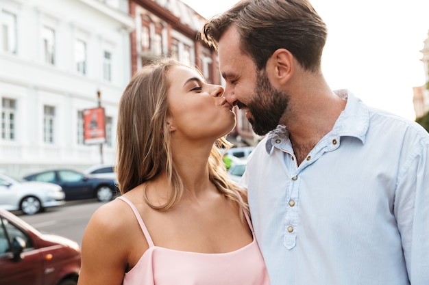 Close up of a happy beautiful couple embracing while standing at the city street, kissing