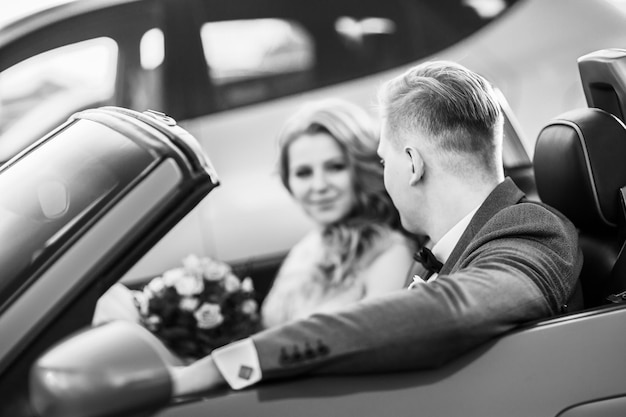 Close up. happy bride and groom sitting in a luxury car. black and white photo