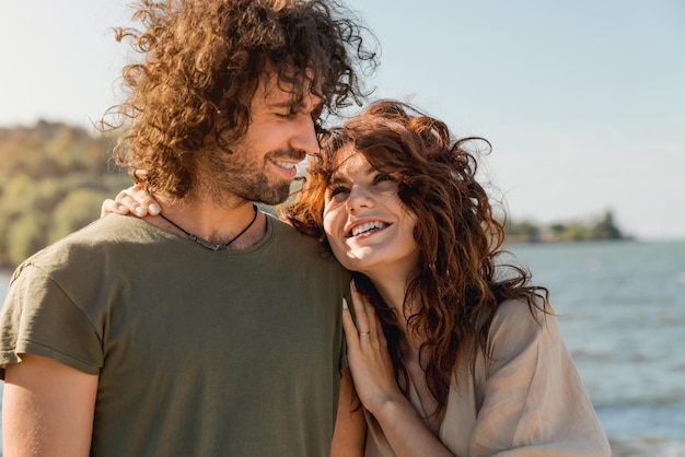 Close up of happy couple hugging and laughing together at the beach