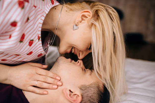 Close-up of happy couple is lying in bed together. Kissing and enjoying the company of each other.