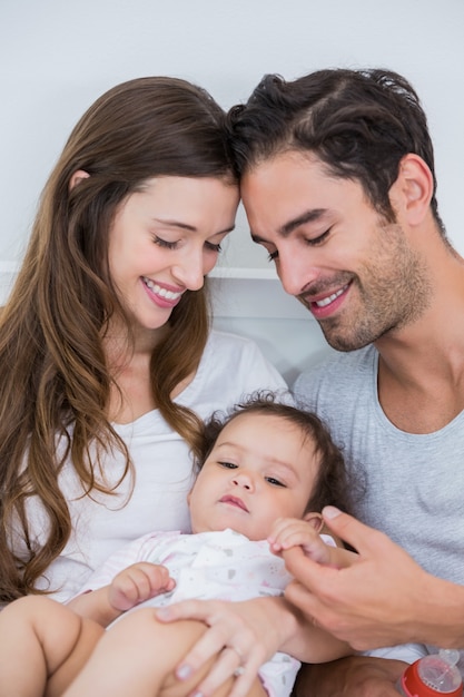 Close-up of happy couple with baby on bed