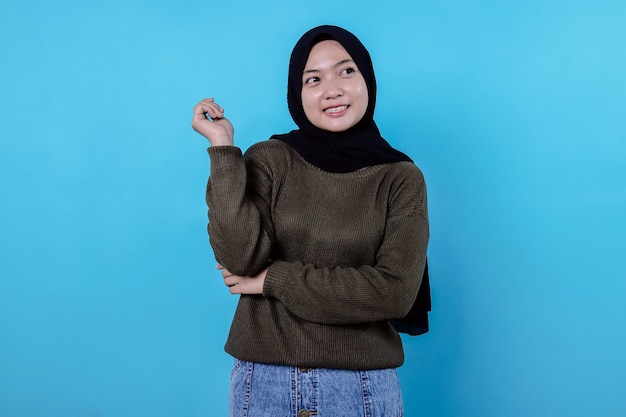 Close-up of happy girl wearing hijab in casual cloth and smiling on blue wall