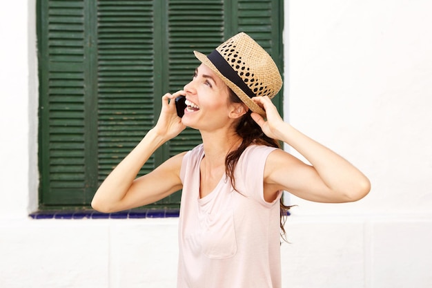 Close up happy woman with hat talking on mobile phone outdoors