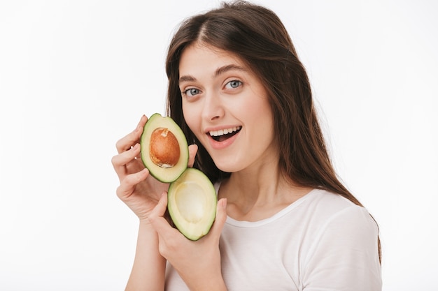 Close up of a happy young beautiful woman isolated, showing fresh avocado