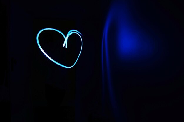 Photo close-up of heart shape light painting against black background