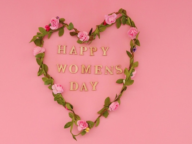 Close-up of heart shape on pink flower against red background with text happy  womens day