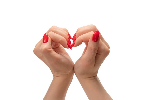 Close up of heart symbol made by woman hands with red nails isolated on white background