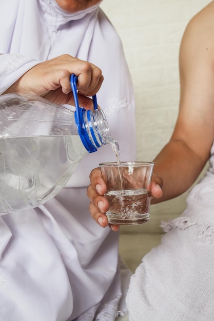 Close up of hijab woman hands pouring zamzam water into the glass