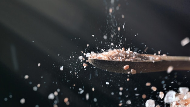 Photo close up of himalayan salt pouring from above on wooden spoon recipe seasoning ingredients