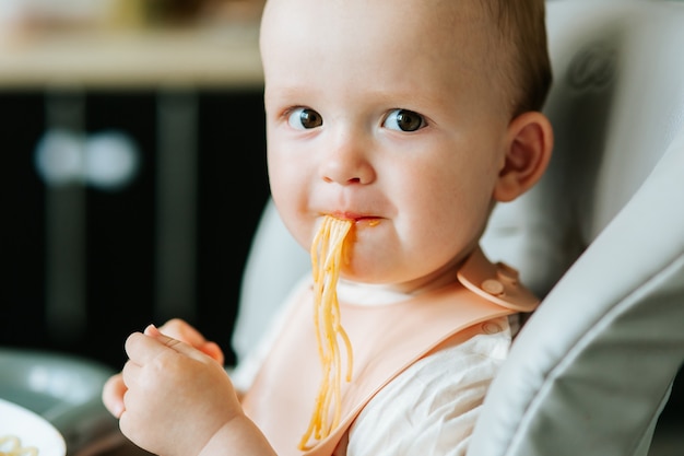 Close up home in the kitchen little boy boy eating spaghetti pasta with red sauce baby boy eating ap...