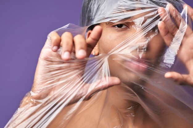 Photo close up horizontal portrait of young man tear up plastic bag with look eyes freedom of transgender