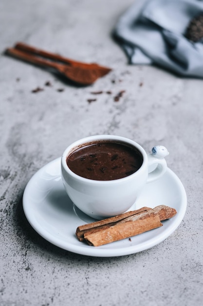 Close up of hot chocolate drink and cinnamon on gray background. 