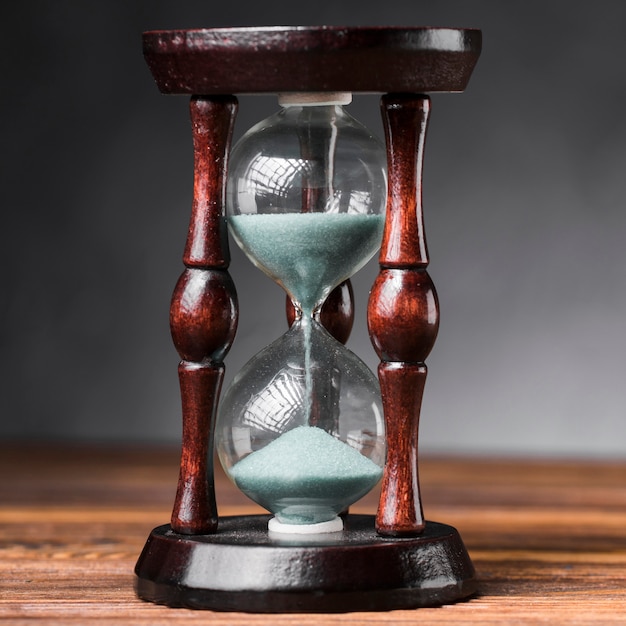 Photo close-up of hour glass on wooden desk