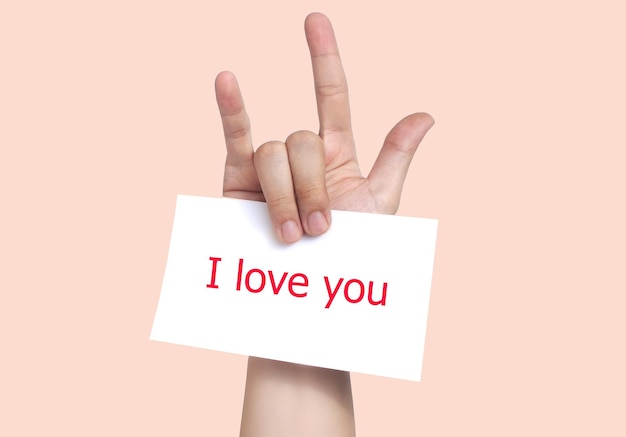 Photo close-up of human hand gesturing while holding paper with text against peach background