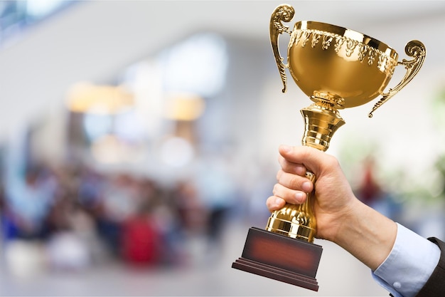 Close-up human hand holding golden Trophy on