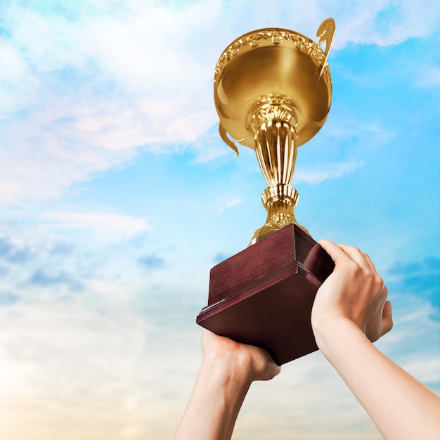 Close-up human hands holding golden Trophy on background